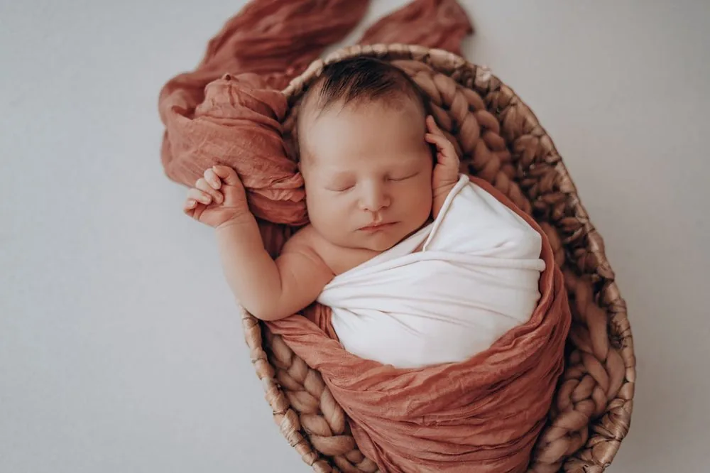 Nouveau-né emmailloté dans un panier en osier, photographe naissance Montpellier